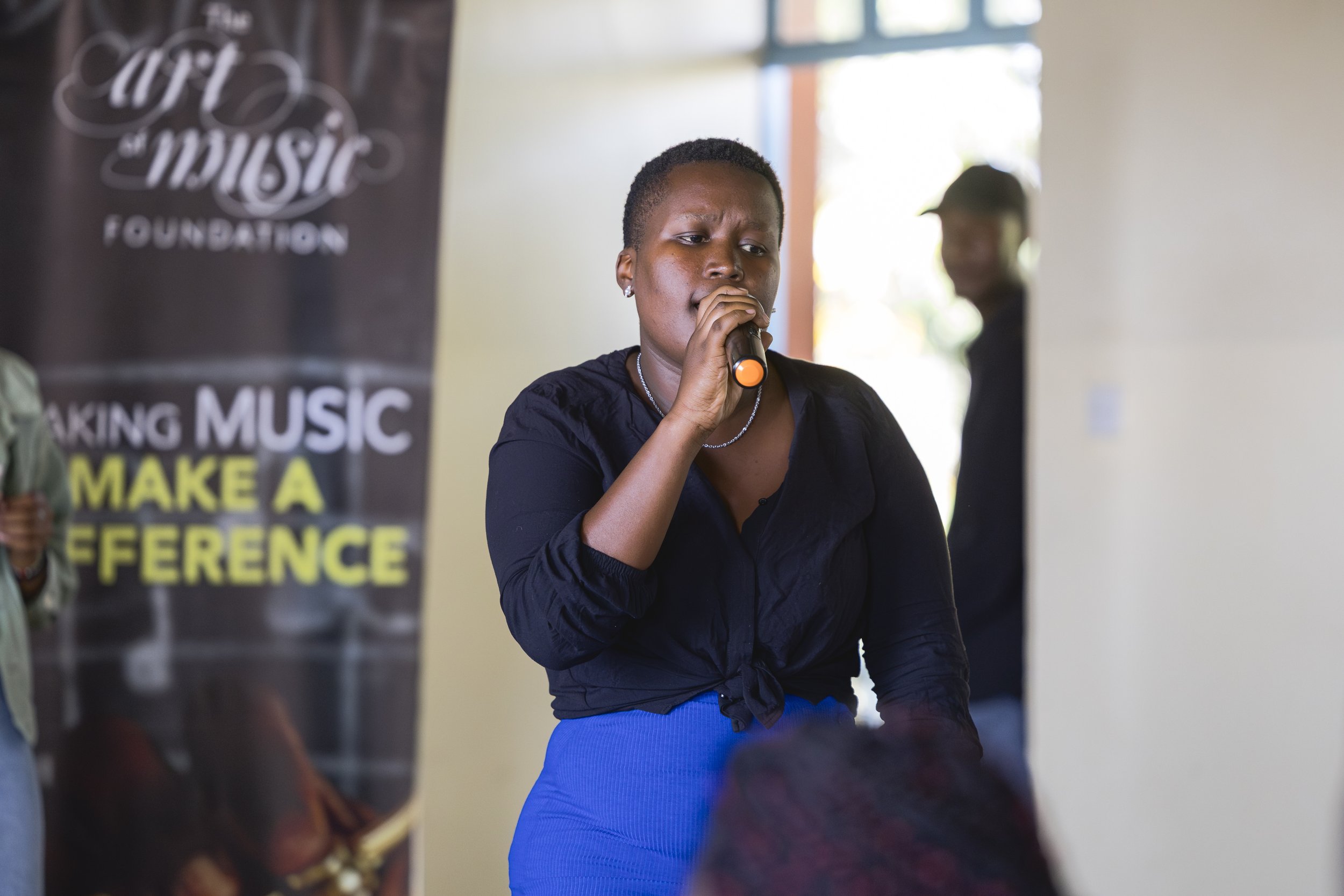 Damackline singing into a handheld microphone during an event.