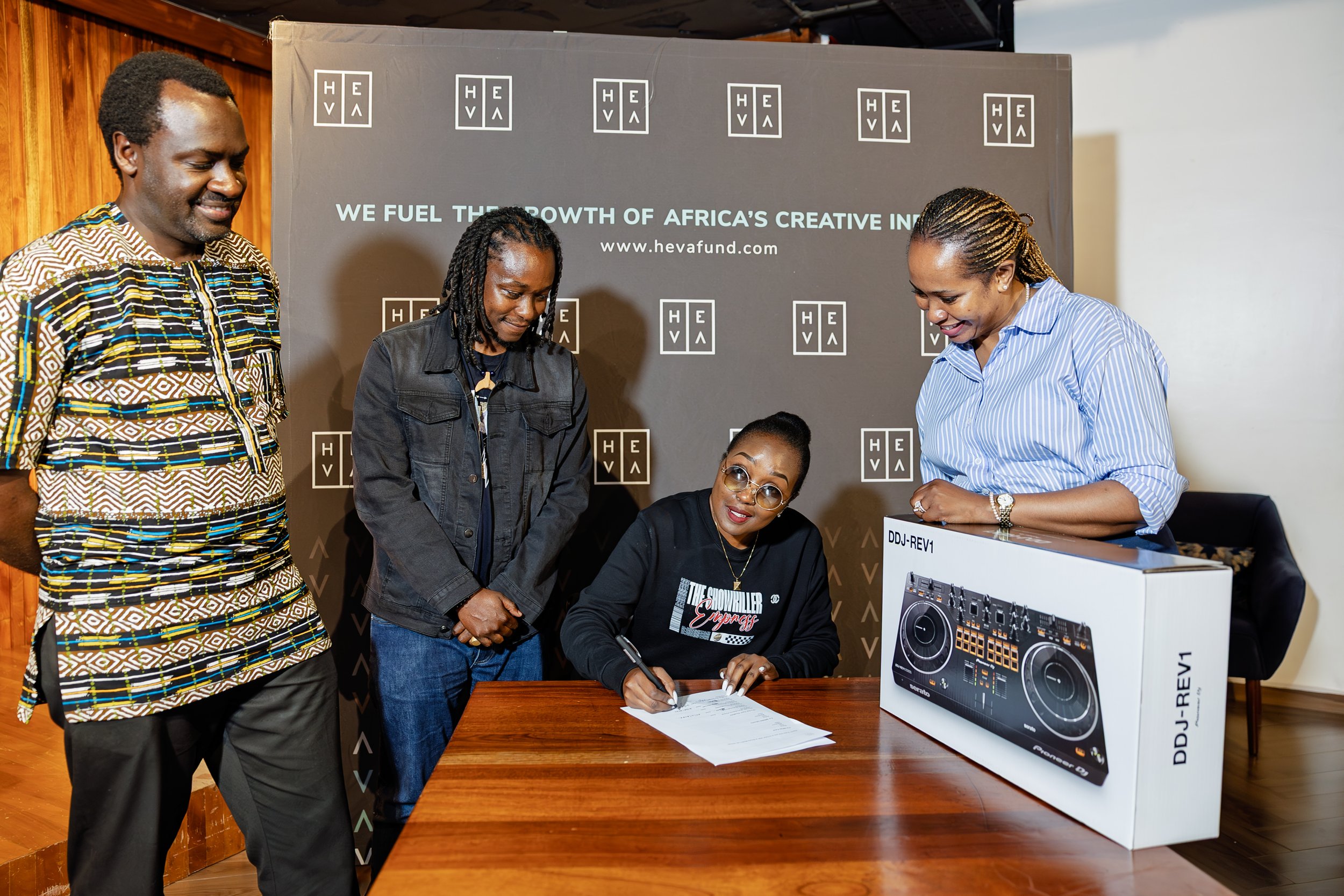 DJ BigStar signing documents beside her new DJ equipment with programme partners.